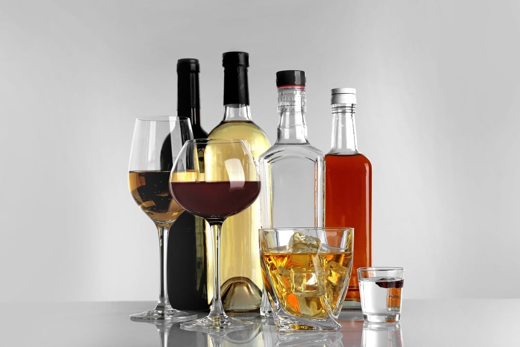 Glasses of Wine and Spirits on Light Background